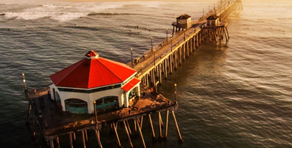 Pier at the beach with a large building with a red roof at the end